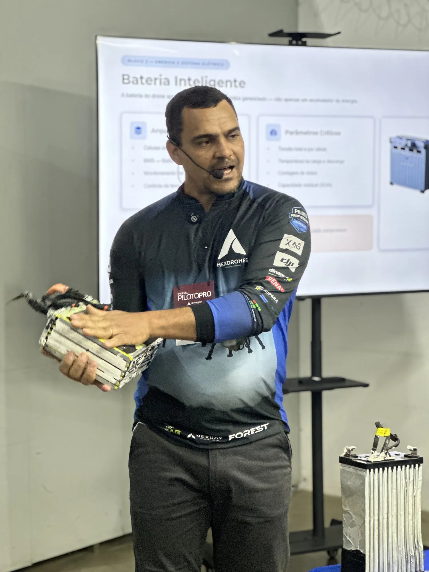 Instrutor apresentando a bateria inteligente de um drone agrícola durante a aula