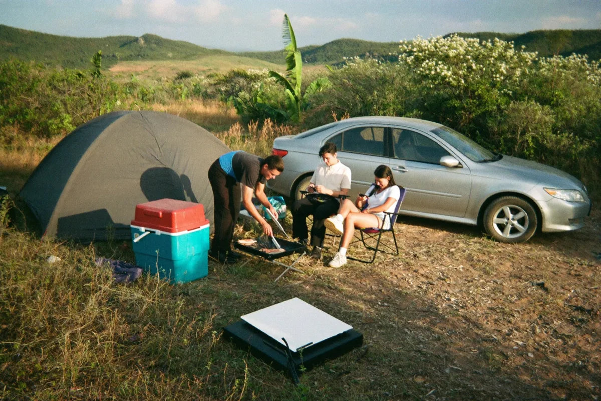 Amigos acampados com barraca e carro ao lado no fim de tarde