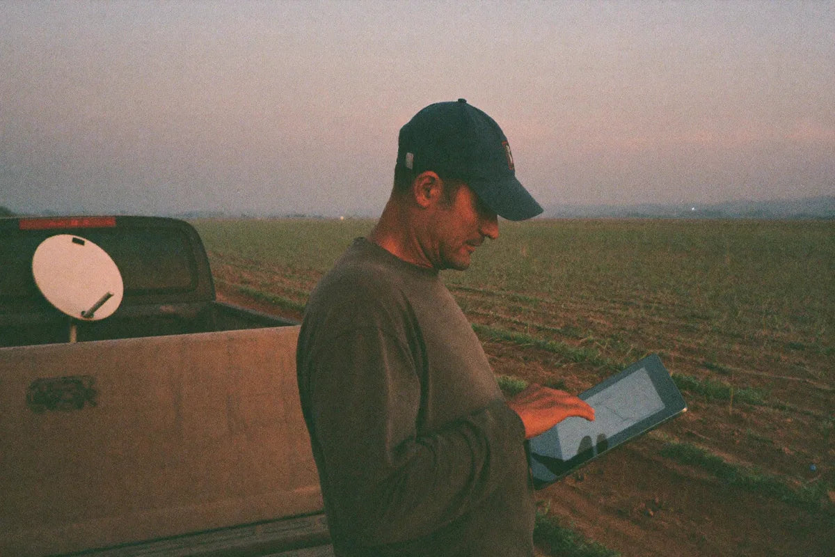 Produtor rural com tablet ao lado da picape na beira da lavoura