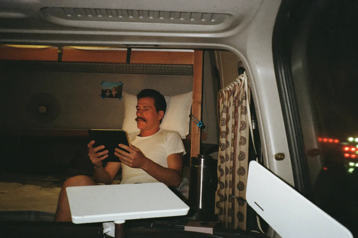 Caminhoneiro na cama da cabine assistindo vídeo no celular à noite