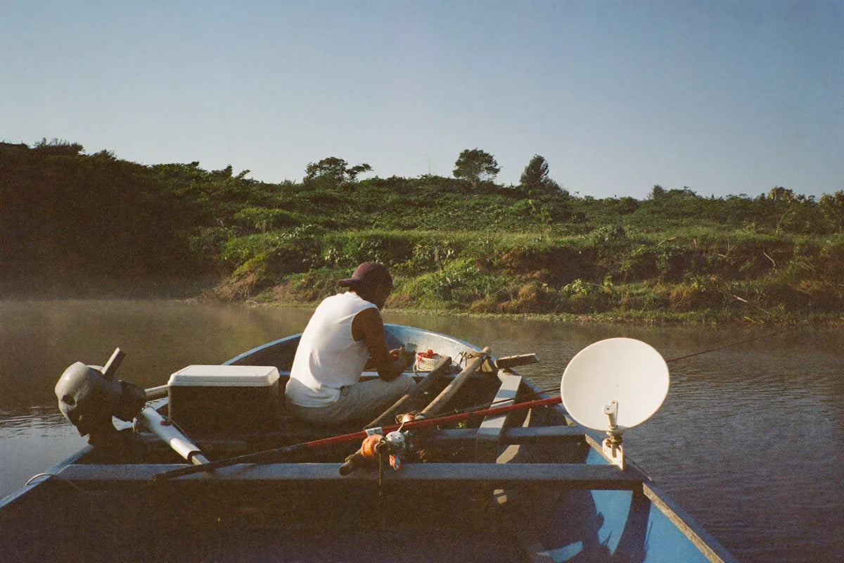 Pescador em barco de alumínio no rio conferindo o celular